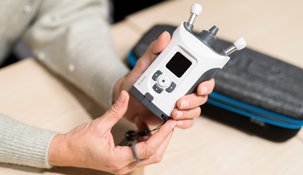Closeup of a woman holding an eye pressure machine for at-home IOP measurement