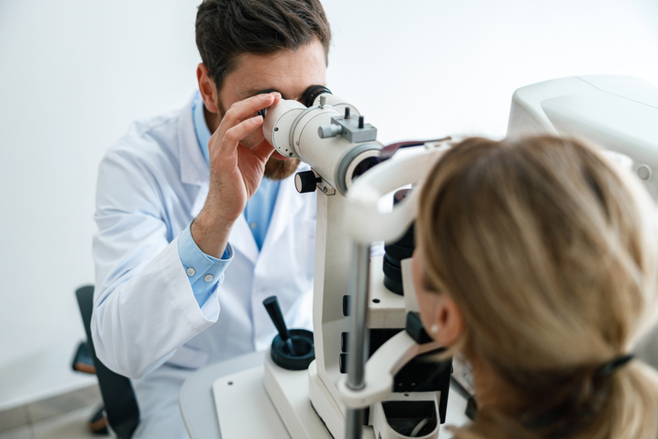 Optometrist conducting a non-contact tonometer eye pressure test on a patient to check IOP